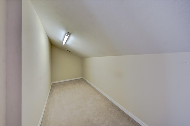 additional living space featuring light carpet and vaulted ceiling