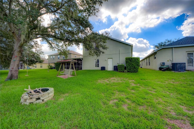 view of yard with a fire pit and central air condition unit