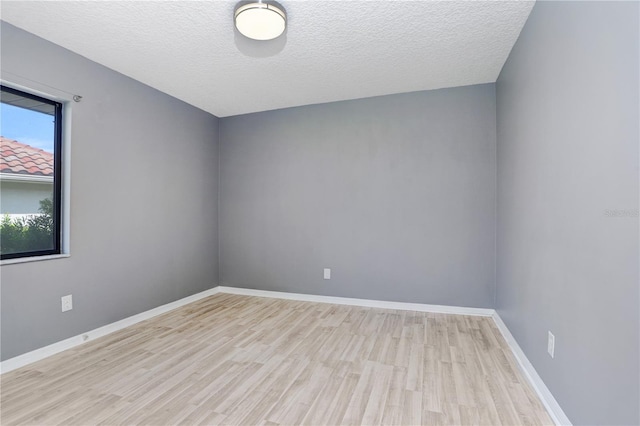 empty room featuring a textured ceiling and light hardwood / wood-style floors