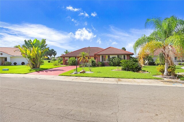 view of front of house featuring a front lawn, decorative driveway, a tile roof, and stucco siding