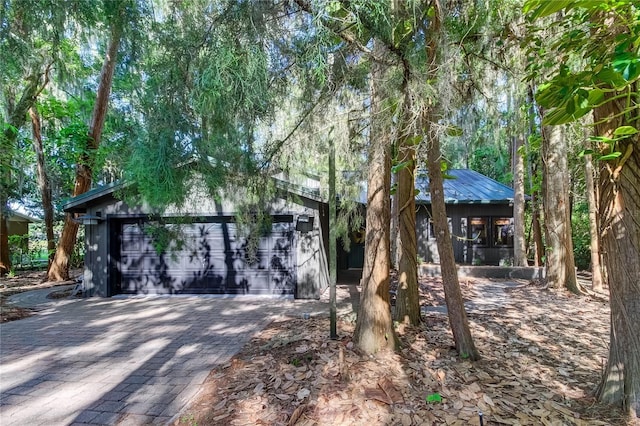 view of property hidden behind natural elements featuring a garage and an outdoor structure