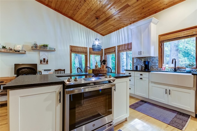 kitchen featuring sink, electric range, white cabinets, and a center island with sink