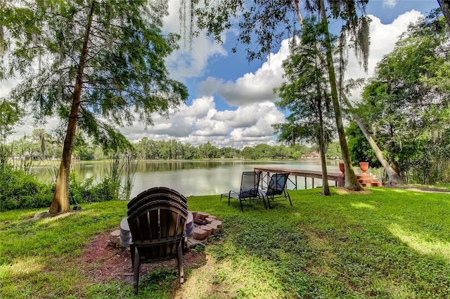 dock area featuring a water view, a yard, and a fire pit