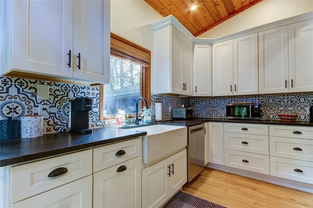 kitchen with sink, dishwasher, backsplash, white cabinets, and vaulted ceiling