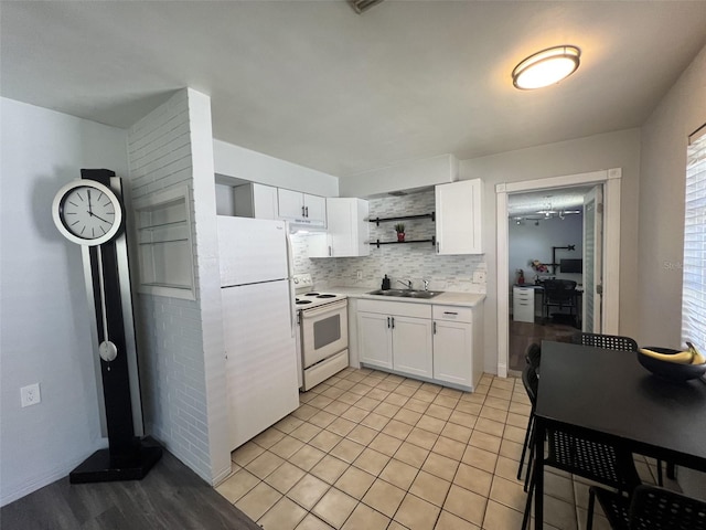 kitchen with white appliances, backsplash, white cabinets, sink, and light tile patterned floors