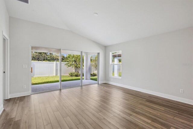 unfurnished room featuring vaulted ceiling, wood finished floors, and baseboards