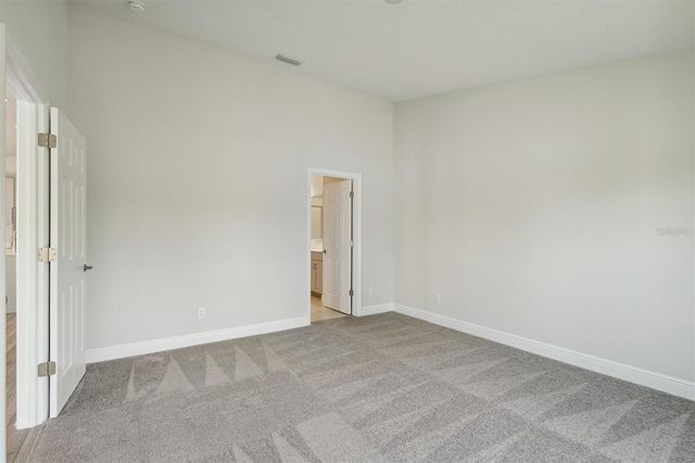 empty room with light carpet, visible vents, and baseboards