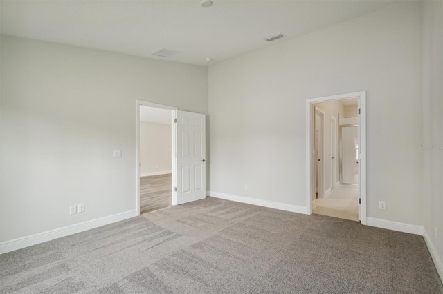 carpeted spare room featuring a high ceiling