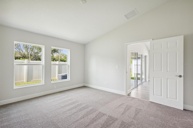 empty room with lofted ceiling, light carpet, and baseboards