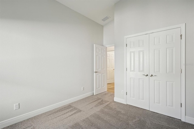 unfurnished bedroom featuring light carpet, high vaulted ceiling, and a closet