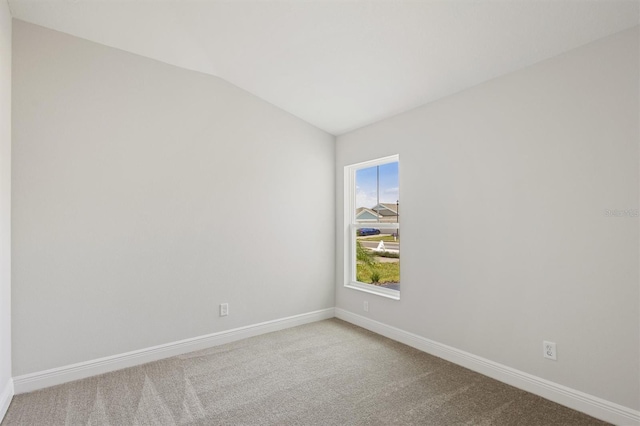 empty room featuring lofted ceiling, carpet, and baseboards