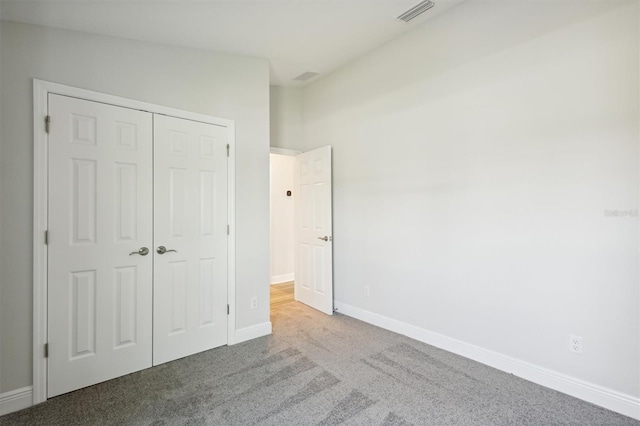 unfurnished bedroom with a closet, visible vents, baseboards, and carpet flooring