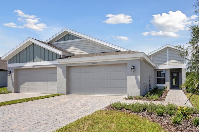 view of front of property with decorative driveway, roof with shingles, stucco siding, an attached garage, and board and batten siding