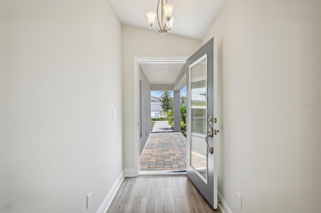 entryway with baseboards, a chandelier, and wood finished floors