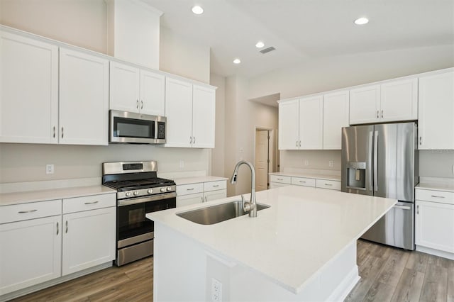 kitchen featuring visible vents, white cabinets, appliances with stainless steel finishes, a kitchen island with sink, and a sink