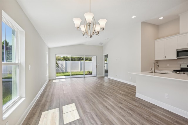 unfurnished living room with a chandelier, recessed lighting, a sink, baseboards, and light wood finished floors