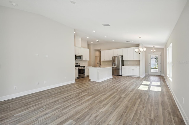 unfurnished living room featuring light hardwood / wood-style flooring, a notable chandelier, sink, and high vaulted ceiling