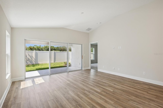 unfurnished room with lofted ceiling, visible vents, light wood-style flooring, and baseboards