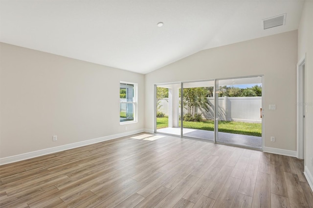 empty room featuring lofted ceiling, light wood-type flooring, visible vents, and baseboards