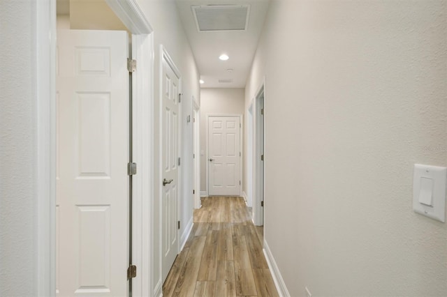 hallway with light wood finished floors, baseboards, visible vents, and recessed lighting