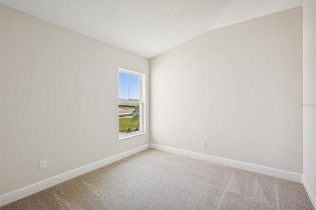 spare room with light carpet, baseboards, and vaulted ceiling