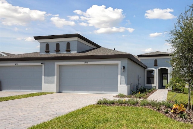 view of front of house with a garage, a front lawn, decorative driveway, and stucco siding