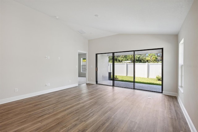 empty room with hardwood / wood-style floors and lofted ceiling