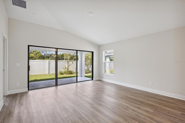 spare room featuring vaulted ceiling and hardwood / wood-style floors