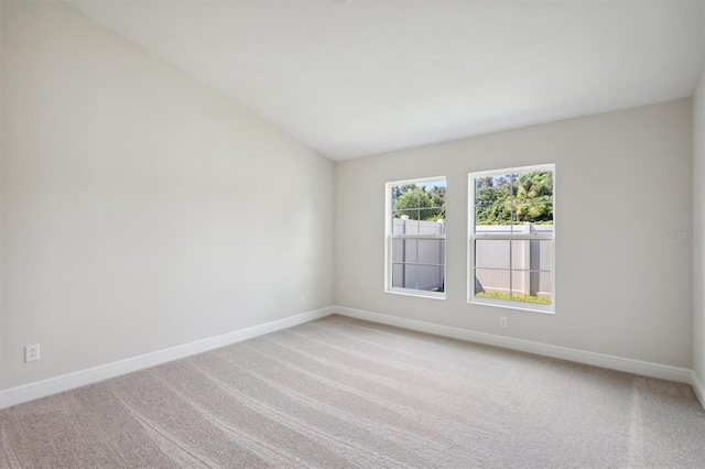 carpeted empty room featuring lofted ceiling