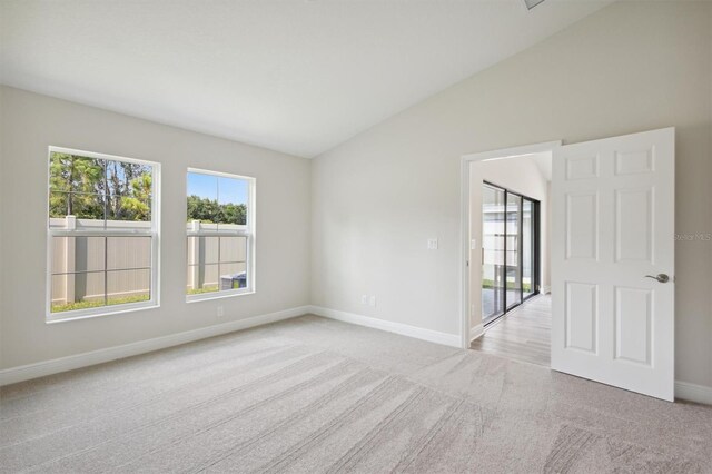 spare room with vaulted ceiling and light colored carpet