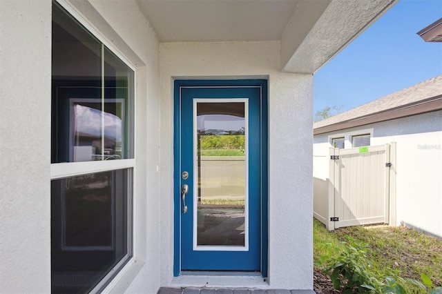 property entrance with a gate and stucco siding