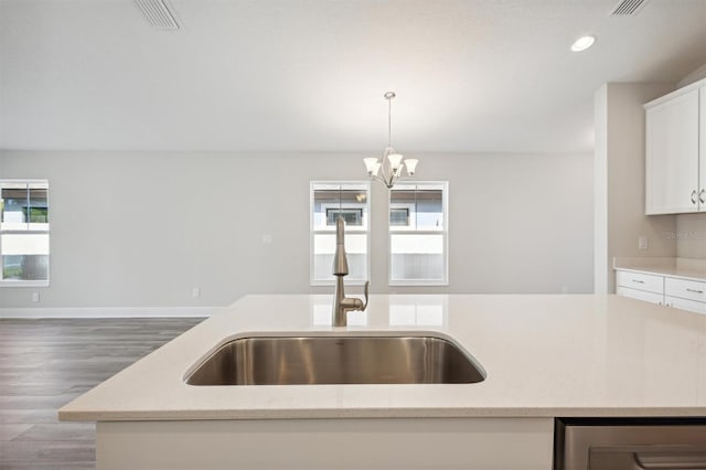 kitchen featuring light stone counters, white cabinetry, hanging light fixtures, hardwood / wood-style flooring, and sink