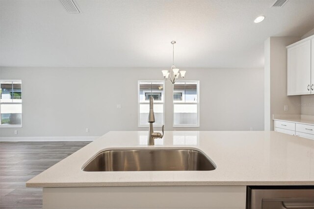 kitchen with visible vents, white cabinets, dark wood-style flooring, decorative light fixtures, and a sink