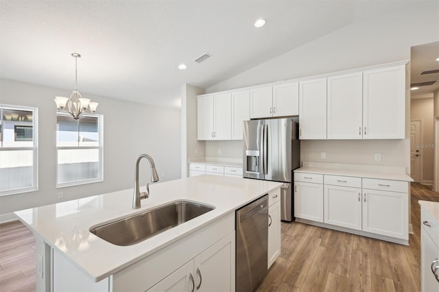 kitchen with stainless steel appliances, light countertops, visible vents, a kitchen island with sink, and a sink