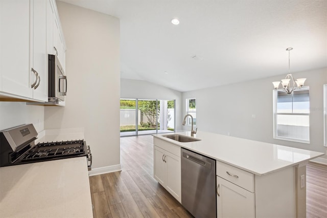 kitchen with stainless steel appliances, a sink, white cabinets, light countertops, and a center island with sink