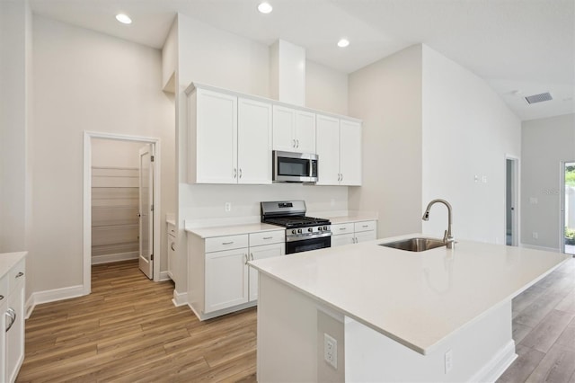 kitchen featuring stainless steel appliances, light countertops, a sink, and an island with sink