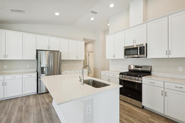 kitchen featuring stainless steel appliances, light countertops, a kitchen island with sink, a sink, and white cabinetry