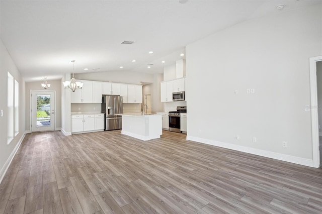 unfurnished living room featuring baseboards, lofted ceiling, a notable chandelier, light wood-type flooring, and a sink