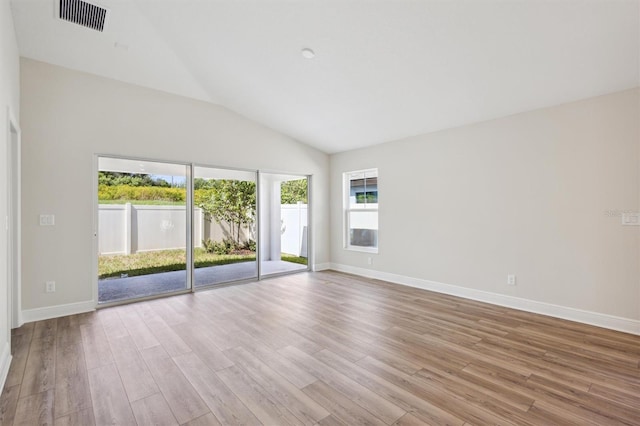 unfurnished room with light wood-style flooring, visible vents, vaulted ceiling, and baseboards