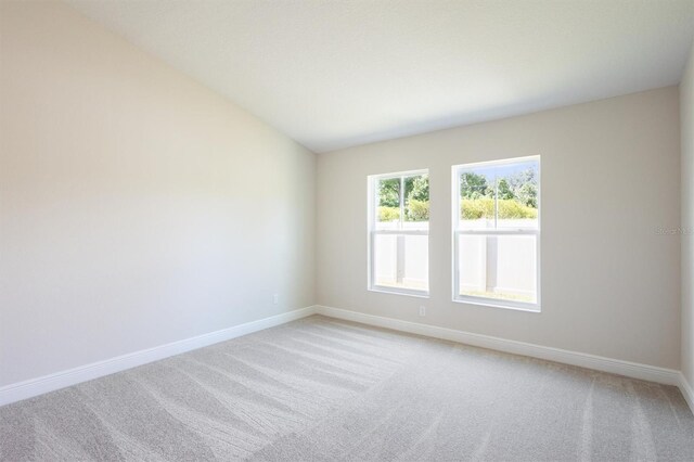 carpeted empty room featuring vaulted ceiling