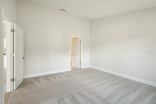 spare room featuring visible vents, light carpet, and baseboards