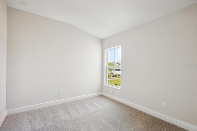 carpeted spare room with lofted ceiling