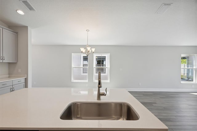 kitchen with gray cabinetry, dark hardwood / wood-style flooring, sink, and decorative light fixtures