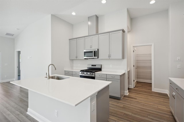 kitchen featuring high vaulted ceiling, sink, stainless steel appliances, and a center island with sink