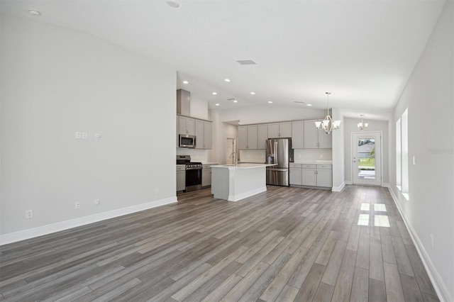 unfurnished living room with a chandelier, vaulted ceiling, baseboards, and wood finished floors