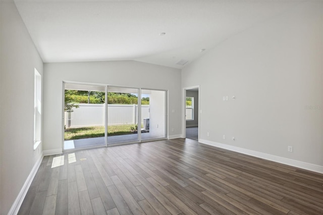 empty room with vaulted ceiling, dark wood-style flooring, and baseboards