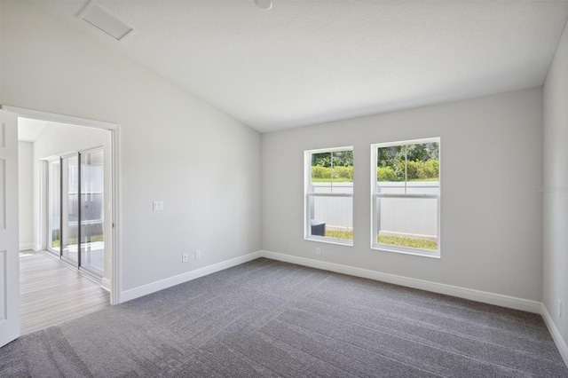 carpeted empty room featuring lofted ceiling