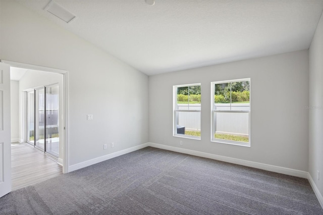 empty room featuring lofted ceiling, carpet flooring, visible vents, and baseboards