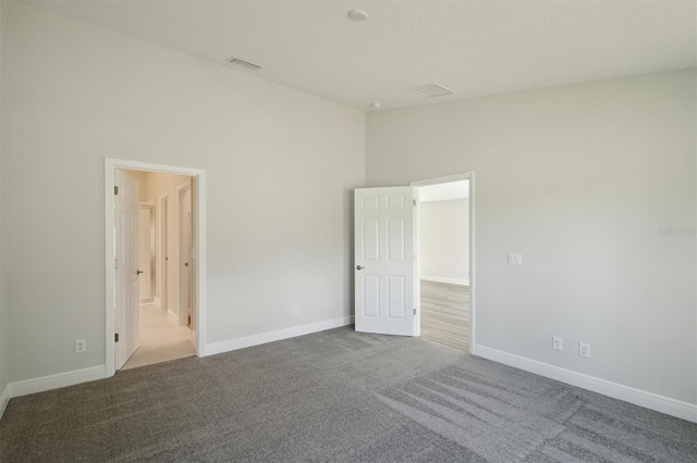 unfurnished bedroom with high vaulted ceiling, carpet flooring, visible vents, and baseboards