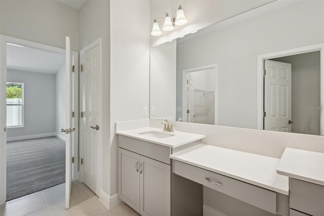 bathroom with a spacious closet, tile patterned flooring, vanity, and baseboards